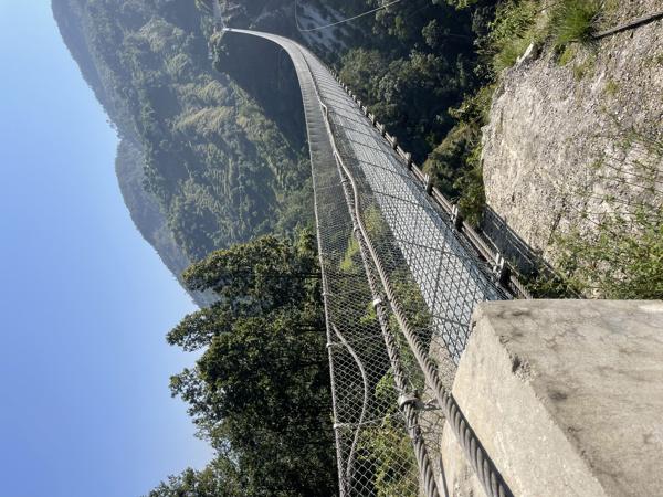 A stunning view of Nepal's suspension bridge stretching high over a gorge, connecting distant peaks with breathtaking scenery.-banrupi